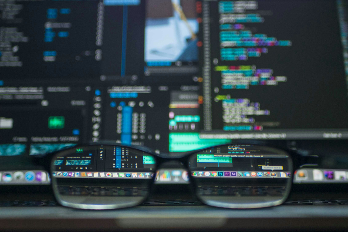 A cover image for AI blog post for tml Partners, showing a pair of glasses in front of a tech-loaded coders screen. Marketing Recruitment