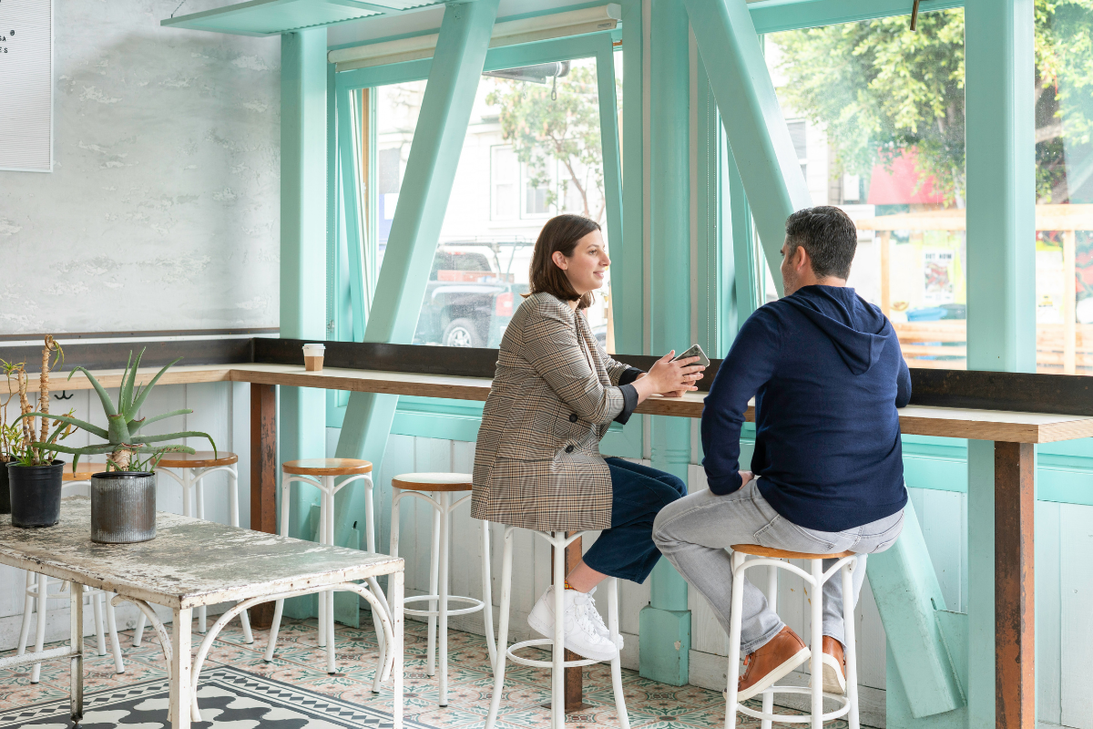 Two people in discussion on bar stools, an image used for tml Partners site for a marketing recruitment blog about Financial Services