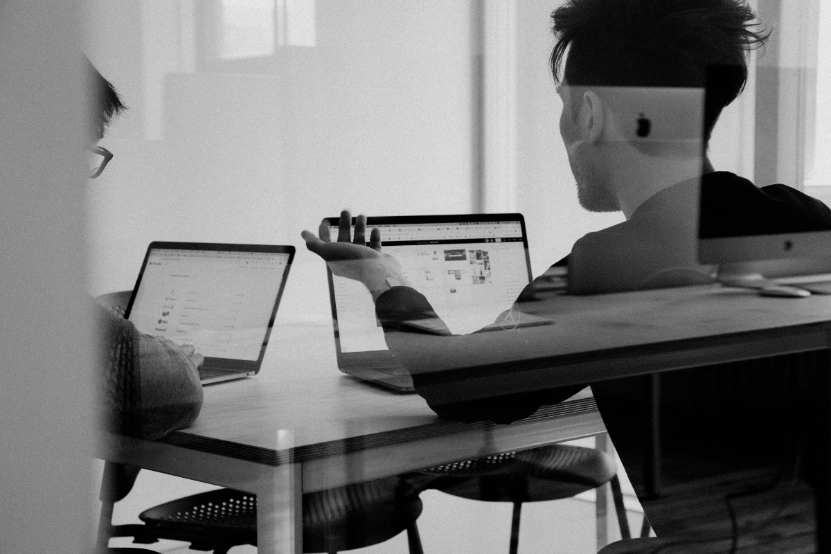 two professionals working on laptops at a desk