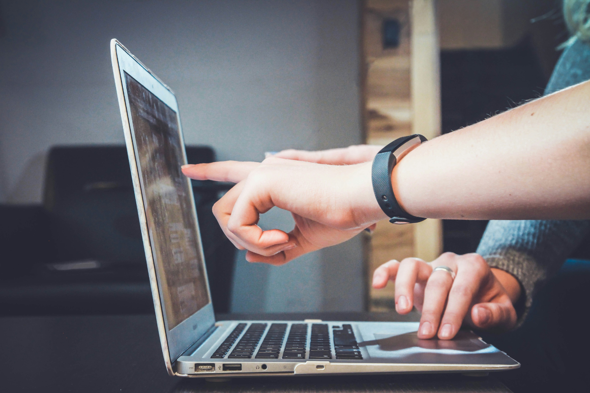 2 people pointing to laptop screen